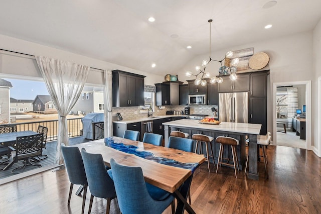 dining room featuring a notable chandelier, a healthy amount of sunlight, dark wood-style floors, and high vaulted ceiling