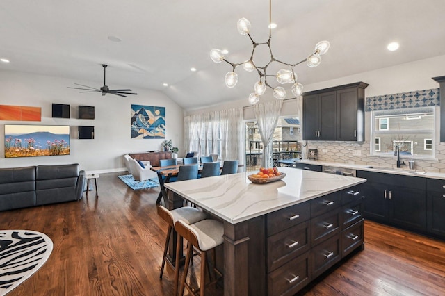 kitchen featuring a breakfast bar, a sink, open floor plan, dark wood finished floors, and lofted ceiling