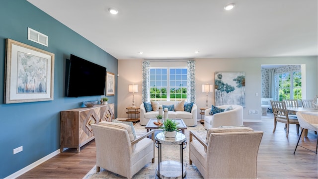 living room featuring a healthy amount of sunlight, visible vents, and wood finished floors