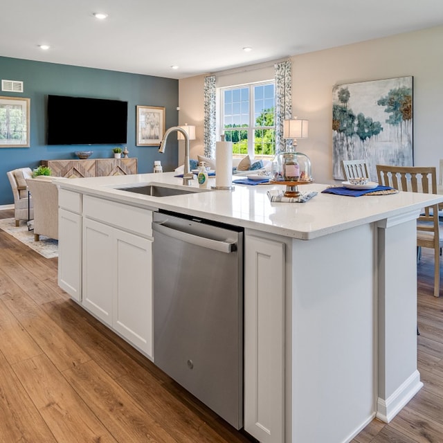 kitchen with dishwasher, a sink, a kitchen island with sink, and light wood-style floors