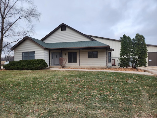 view of front facade with roof with shingles and a front yard