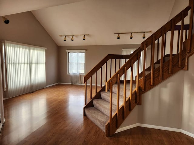 stairway with lofted ceiling, wood finished floors, and baseboards