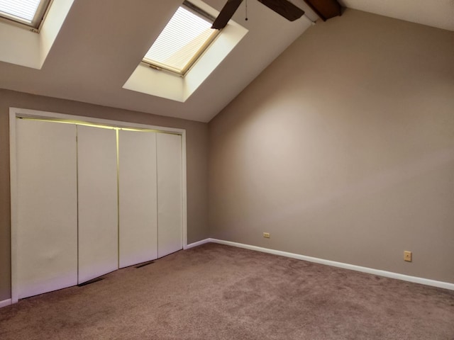 unfurnished bedroom featuring carpet floors, lofted ceiling with skylight, baseboards, and a closet