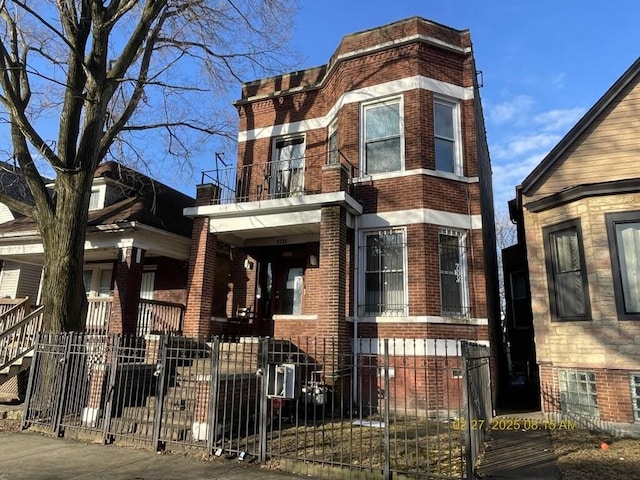 view of front of house with a balcony, fence, and brick siding