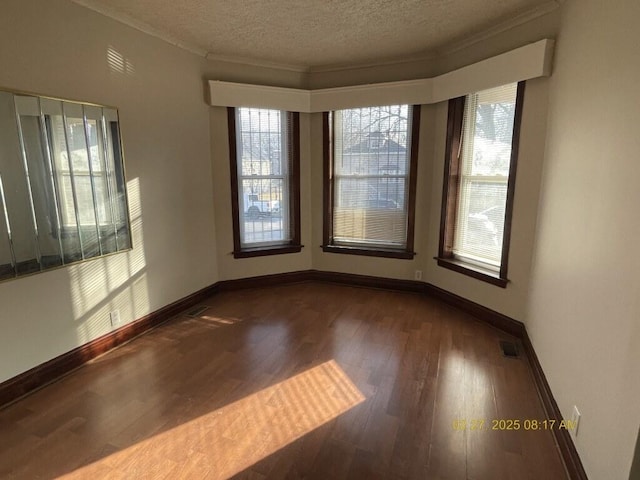 empty room with baseboards, a textured ceiling, visible vents, and wood finished floors