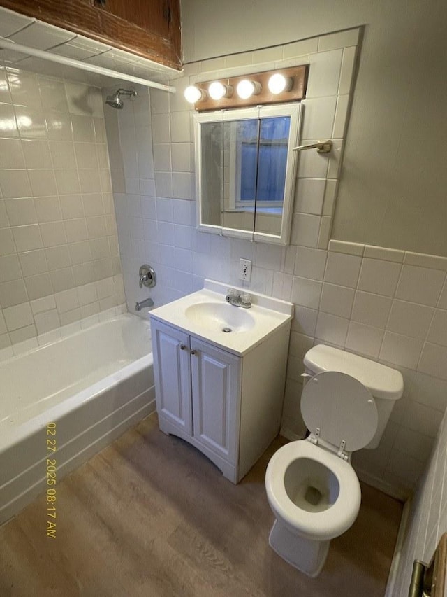 full bath with toilet, shower / bathing tub combination, tile walls, and wood finished floors