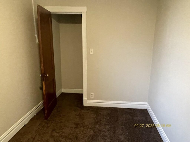 interior space with dark colored carpet and baseboards