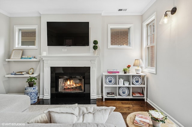 living area featuring visible vents, crown molding, a lit fireplace, and wood finished floors