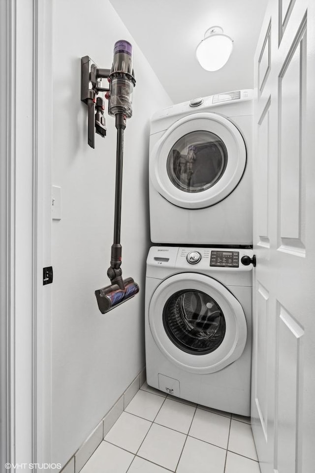 washroom with stacked washer / dryer, laundry area, baseboards, and light tile patterned floors