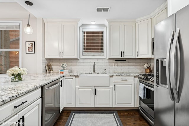 kitchen with visible vents, decorative backsplash, appliances with stainless steel finishes, white cabinets, and a sink