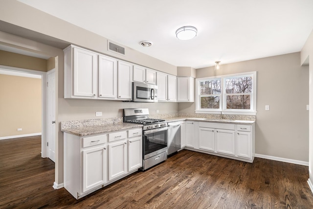 kitchen with dark wood-style floors, stainless steel appliances, visible vents, white cabinetry, and a sink