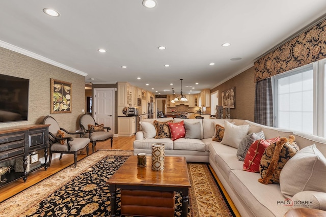 living area featuring a notable chandelier, recessed lighting, crown molding, and light wood-style floors