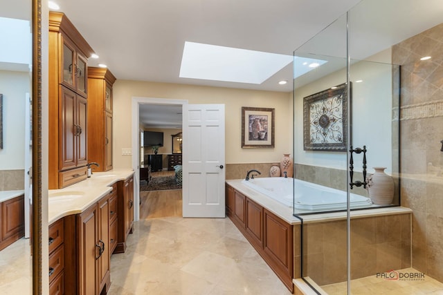 bathroom featuring vanity, a skylight, recessed lighting, a tile shower, and a bath