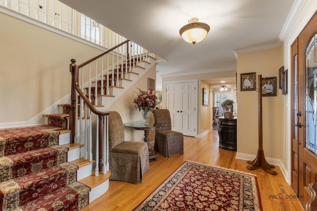 entrance foyer featuring stairs, wood finished floors, baseboards, and ornamental molding