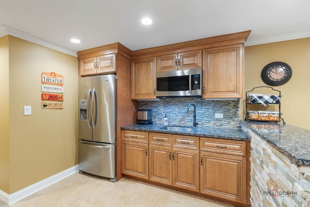 kitchen with dark stone countertops, a sink, stainless steel appliances, brown cabinets, and backsplash