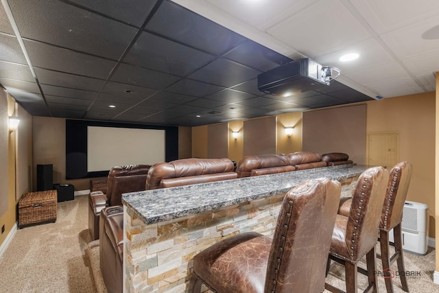 carpeted home theater featuring a paneled ceiling and baseboards