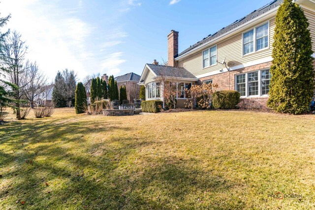 back of house featuring a lawn and brick siding