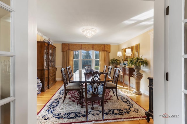 dining space with baseboards, crown molding, and light wood-style floors