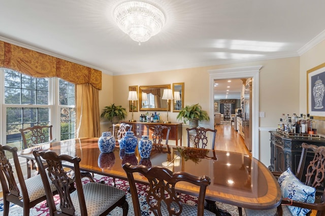 dining space featuring light wood finished floors, a notable chandelier, and ornamental molding