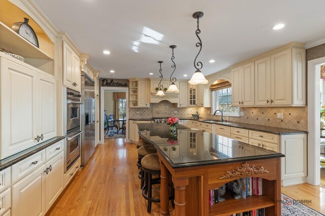 kitchen featuring open shelves, cream cabinets, and a sink