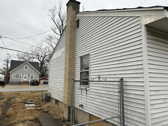 view of property exterior featuring a chimney and fence