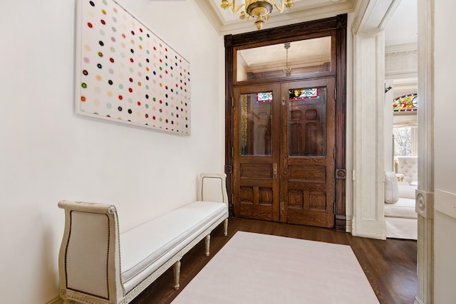 foyer with a chandelier, crown molding, and wood finished floors