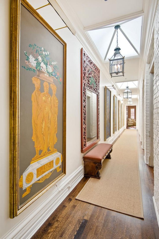 hall with ornamental molding, a notable chandelier, baseboards, and wood finished floors