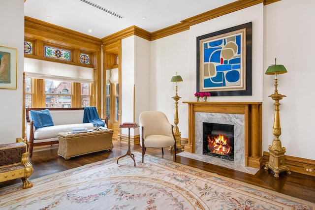 sitting room with wood finished floors, crown molding, and a premium fireplace