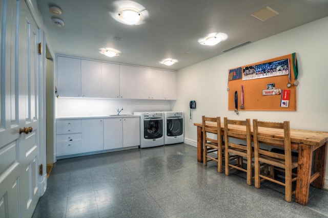 laundry area featuring cabinet space, visible vents, dark floors, washing machine and dryer, and a sink