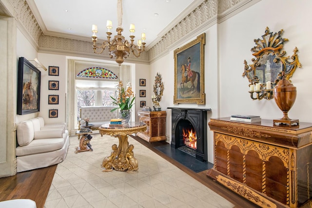 living area featuring an inviting chandelier, a fireplace with flush hearth, ornamental molding, and wood finished floors
