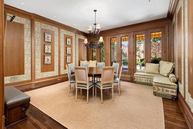 dining room with wallpapered walls, ornamental molding, dark wood finished floors, and an inviting chandelier