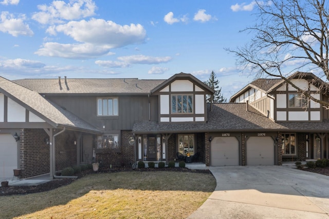 view of front of house with a front lawn, roof with shingles, concrete driveway, an attached garage, and brick siding