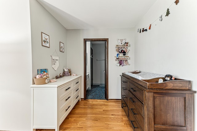 corridor featuring light wood-style flooring and baseboards