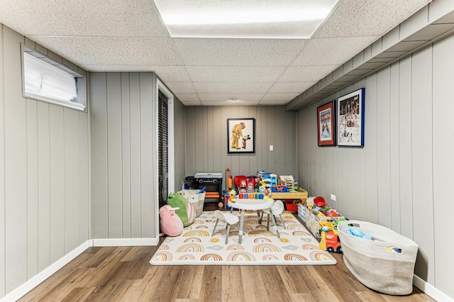 game room featuring a paneled ceiling, baseboards, and wood finished floors