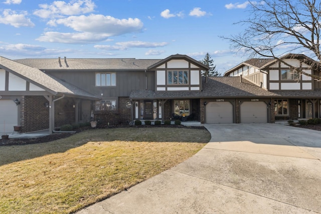 tudor house featuring driveway, a front lawn, a shingled roof, a garage, and brick siding