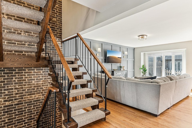 stairway with wood finished floors and brick wall