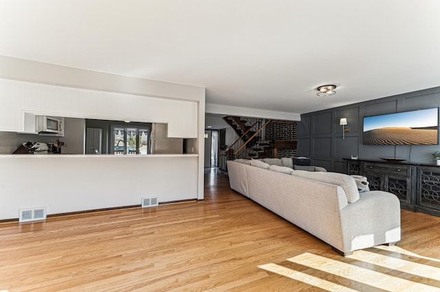 living area with visible vents, stairs, and wood finished floors