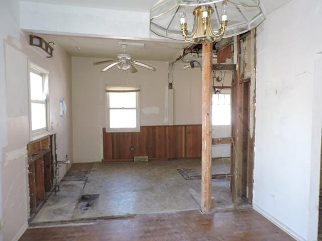 empty room with a wainscoted wall, a notable chandelier, and wood walls