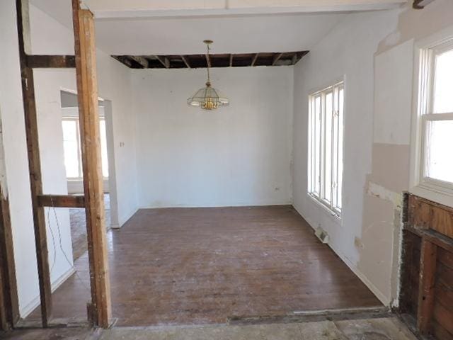 unfurnished dining area with beam ceiling and wood finished floors