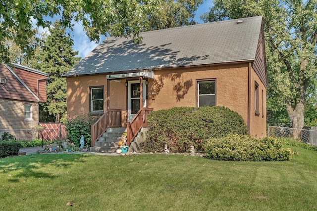 view of front of property with fence, a front lawn, and stucco siding