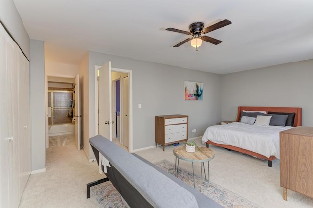 bedroom with light carpet, ceiling fan, baseboards, and connected bathroom