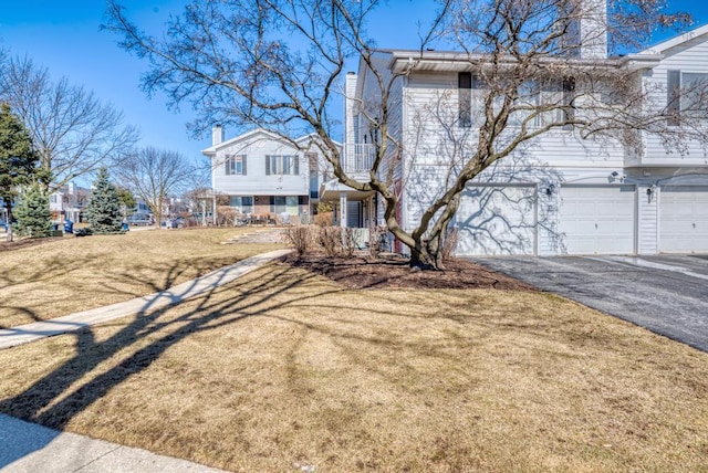 view of front of house with aphalt driveway, an attached garage, and a front yard