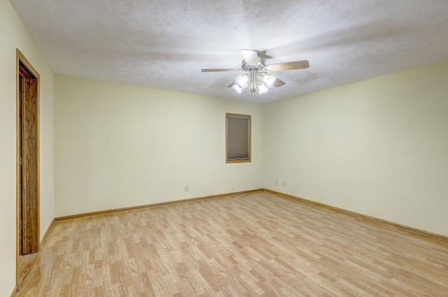 empty room with a ceiling fan, light wood-type flooring, a textured ceiling, and baseboards