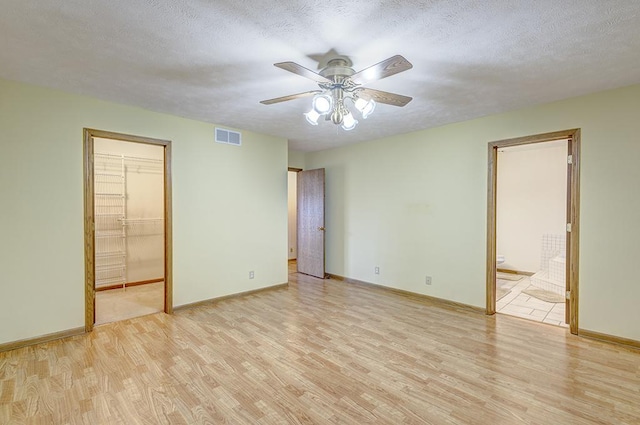 unfurnished bedroom with light wood-type flooring, baseboards, visible vents, and a textured ceiling