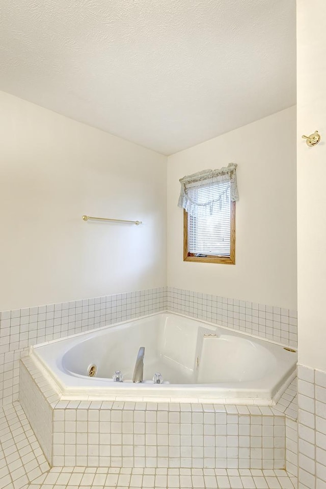 full bath with a whirlpool tub and a textured ceiling