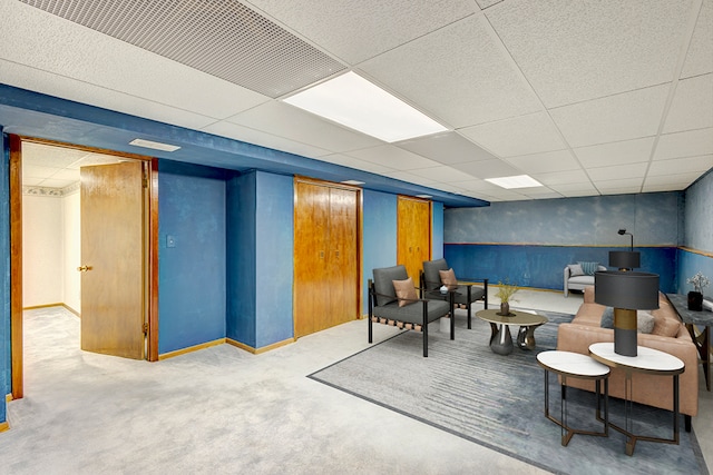 living area featuring wainscoting, a drop ceiling, and carpet flooring