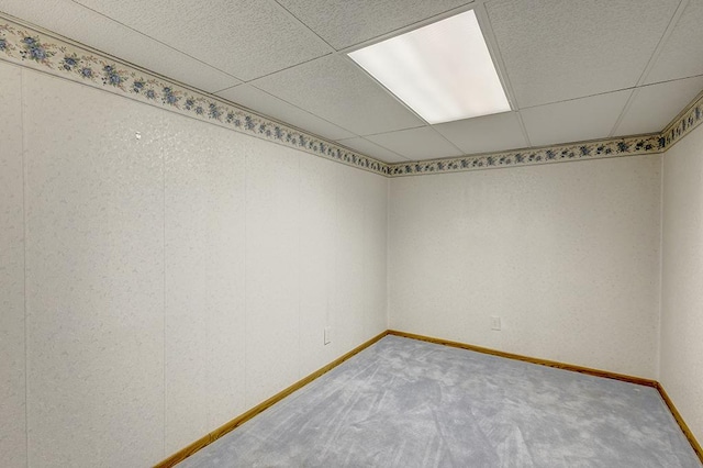 carpeted spare room with a drop ceiling and baseboards