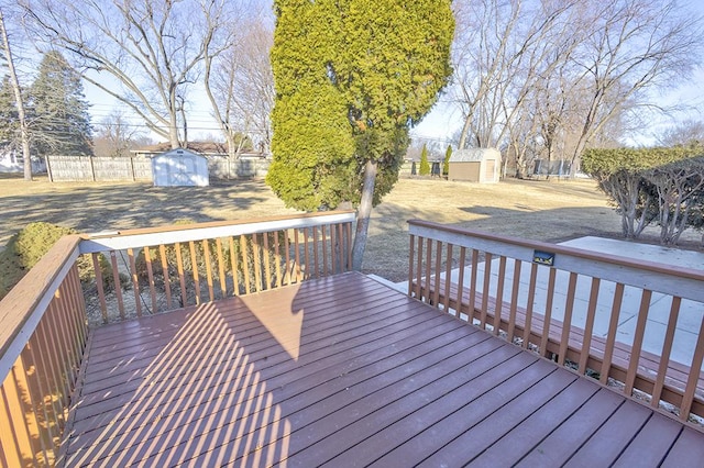 wooden terrace featuring fence, a storage unit, and an outdoor structure