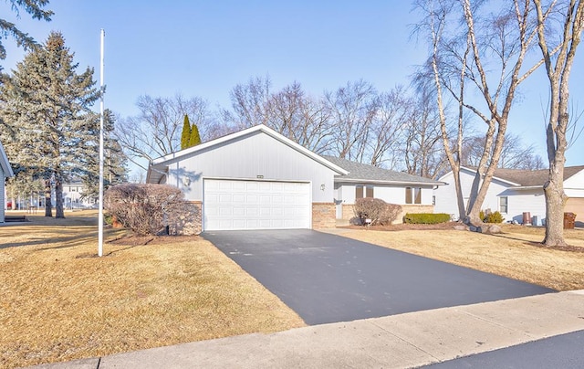 ranch-style house with aphalt driveway, a front lawn, an attached garage, and brick siding