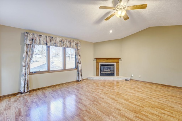 unfurnished living room featuring lofted ceiling, a textured ceiling, wood finished floors, visible vents, and a glass covered fireplace